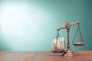 Scales of justice hold money in one side as compensation for whistleblower retaliation