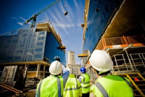 Workers look upward while on a construction site for a government contract