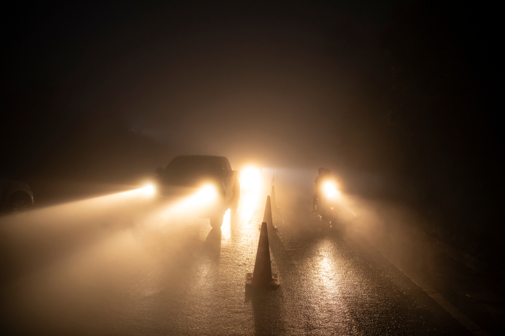 Man is on his knees on the ground being handcuffed Cars in fog and motorcycle lane